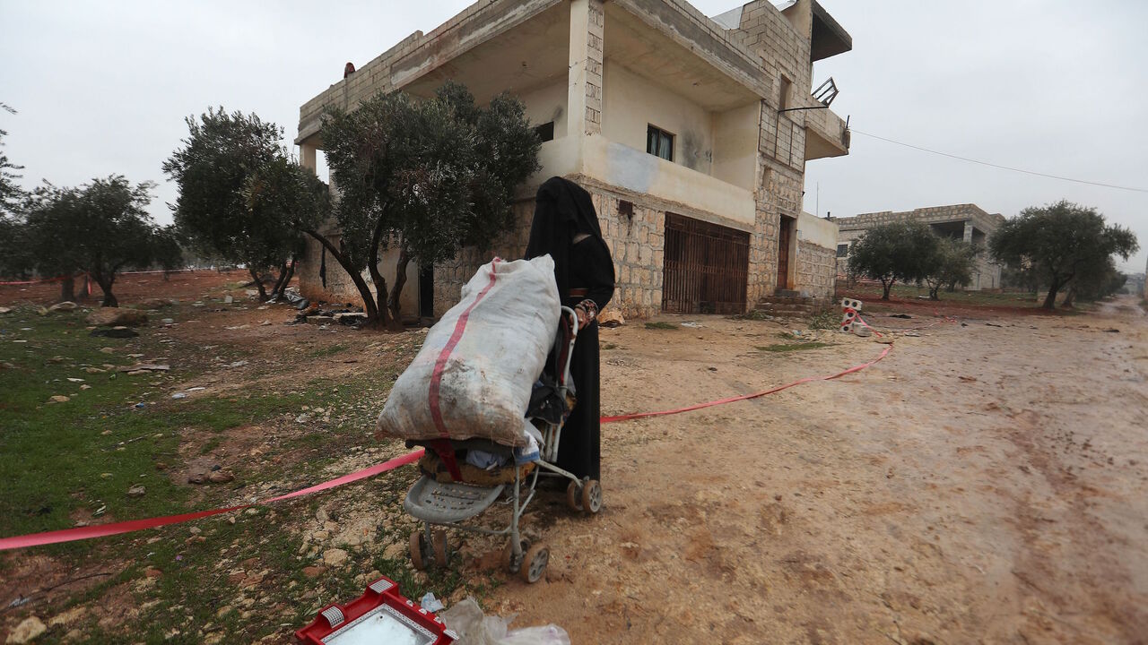 A fully veiled woman collects items near the house in which the leader of Islamic State (IS) group Amir Mohammed Said Abd al-Rahman al-Mawla, aka Abu Ibrahim al-Hashimi al-Qurashi died during a raid by US special forces, in the town of Atme in Syria's northwestern province of Idlib, on Feb. 4, 2022. 