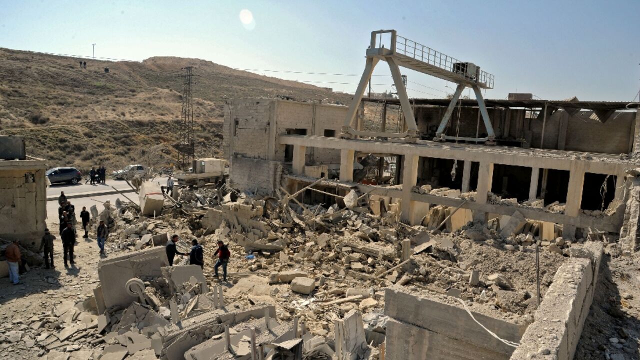 A handout picture released by the official Syrian Arab News Agency (SANA) on March 7, 2022, shows people inspecting a damaged building following Israeli missile strikes before dawn near the capital Damascus