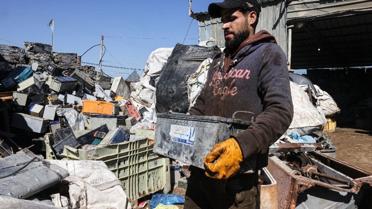 A Palestinian man picks discarded batteries to resell for recycling in the Gaza Strip; batteries are an essential power source in Gaza, where public electricity supply is sparse