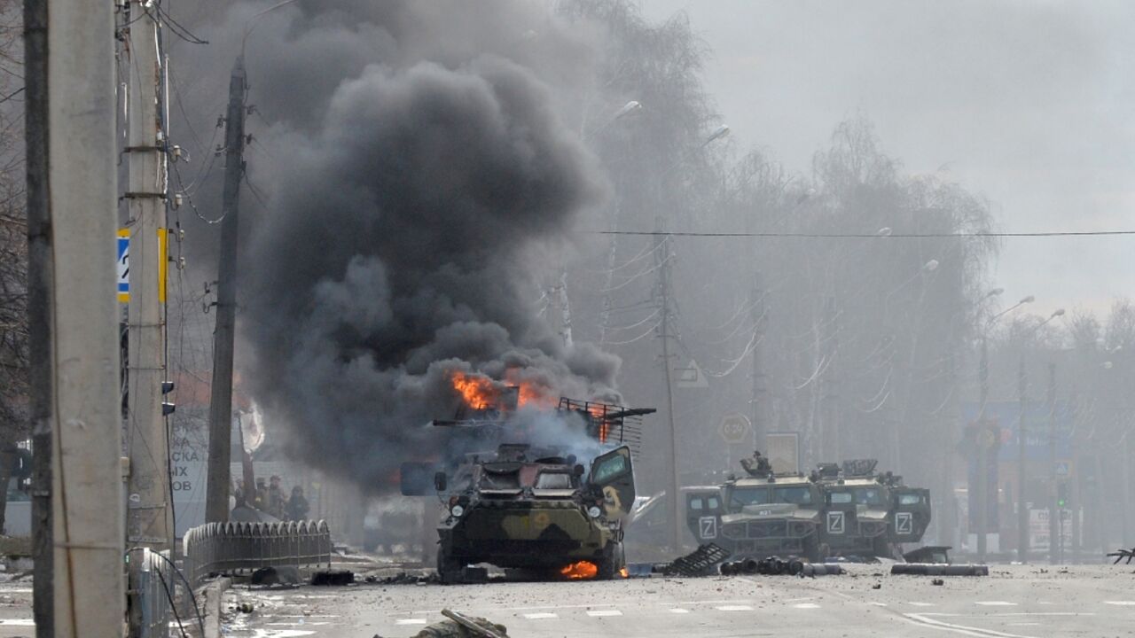 A Russian armoured personnel carrier burns next to an unidentified soldier's body in Kharkiv, Ukraine's second biggest city, following street battles
