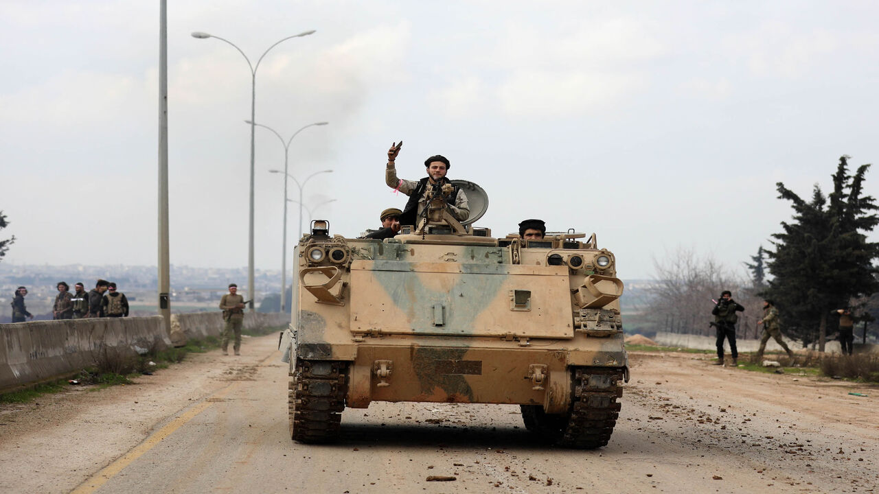 Members of the Syrian National Army, an alliance of Turkey-backed rebel groups, ride in an armored personnel carrier in the town of Sarmin as they take part in a military offensive on the village of Nayrab following an artillery barrage fired by Turkish forces, near Idlib, Syria, Feb. 24, 2020.