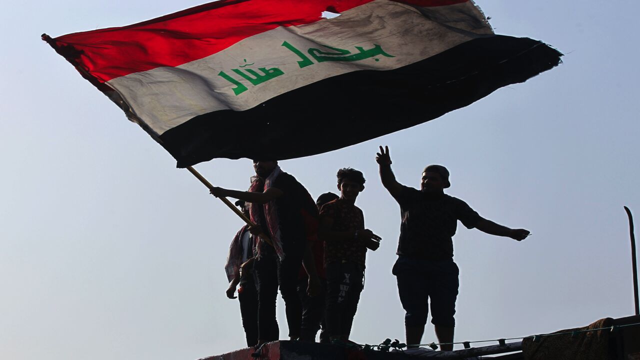 Iraqi demonstrators wave a flag as they gather in Tahrir Square.