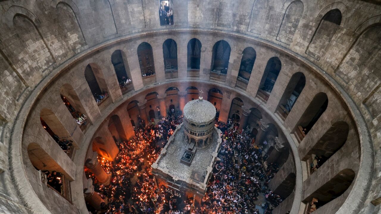 Orthodox Christians gather with lit candles around the Edicule, traditionally believed to be the burial site of Jesus Christ, during the Holy Fire ceremony at Jerusalem's Holy Sepulchre church