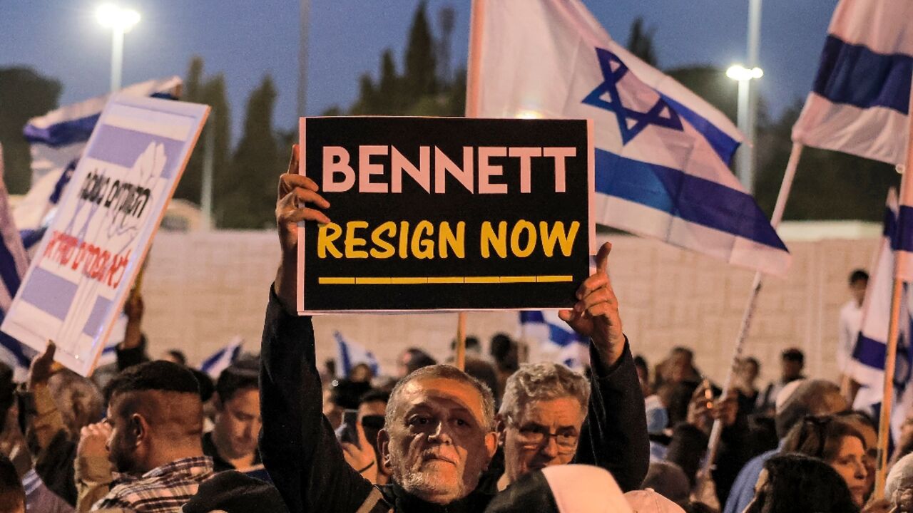 A man holds up a sign reading in English "[Israeli Prime Minister Naftali] Bennett resign now" during an anti-government protest by Israeli right-wing supporters in Jerusalem