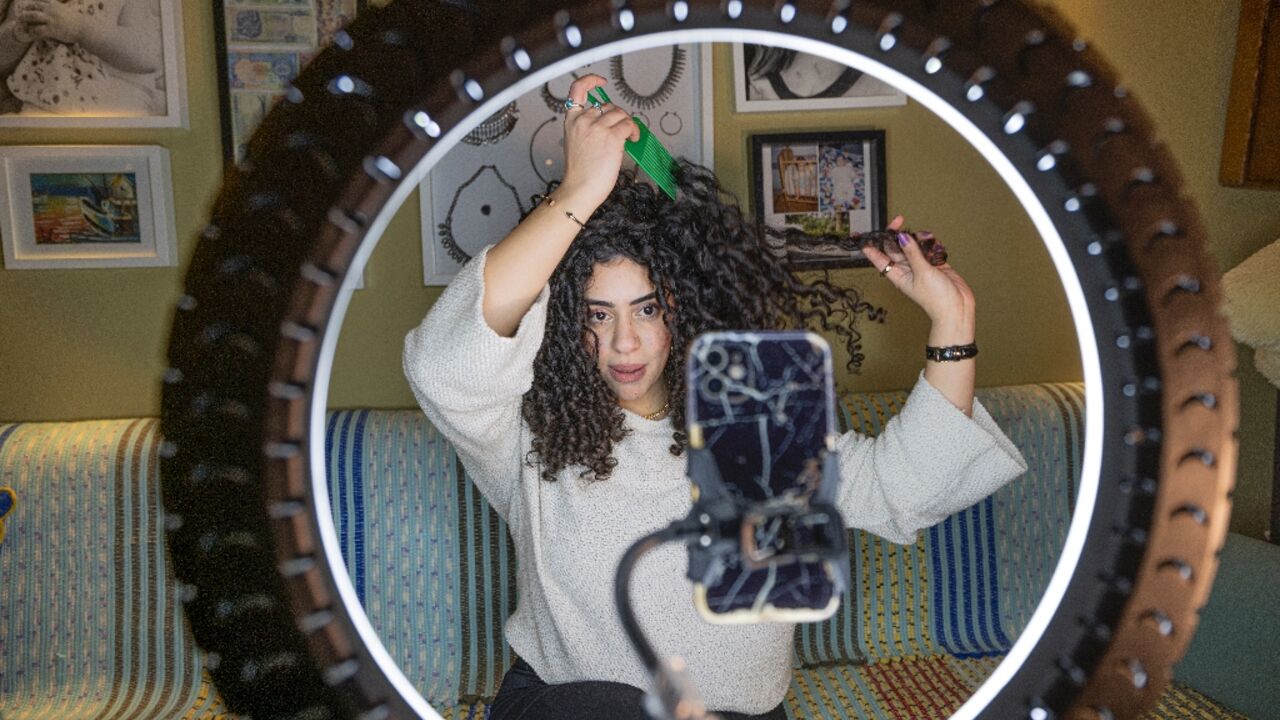 Mariam Ashraf, a teacher and "natural hair influencer", combs her hair during a livestream to her more than 90,000 followers