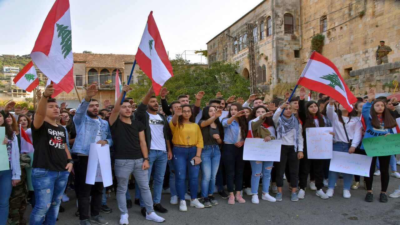 Lebanese students wave the national flag during an anti-government demonstration in the southern village of Hasbaya, Lebanon, Nov. 8, 2019.