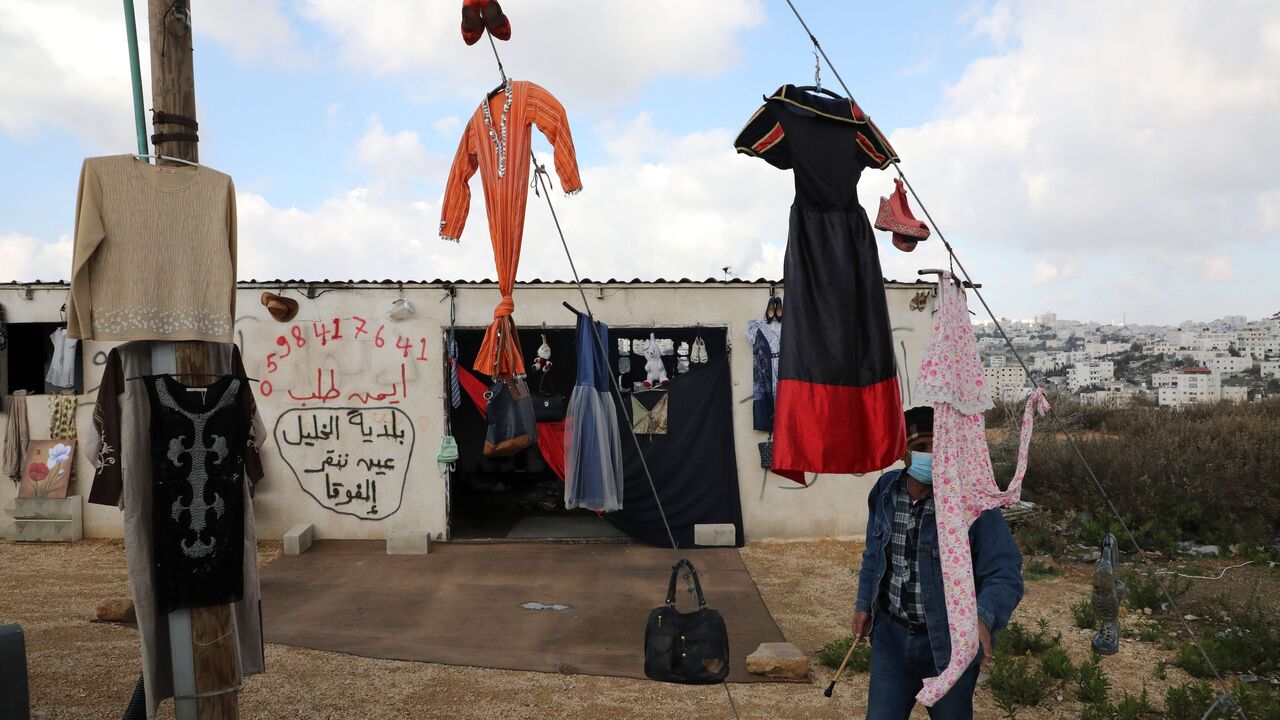 Palestinian man hangs clothing and other items to sell with the hope of getting some income.
