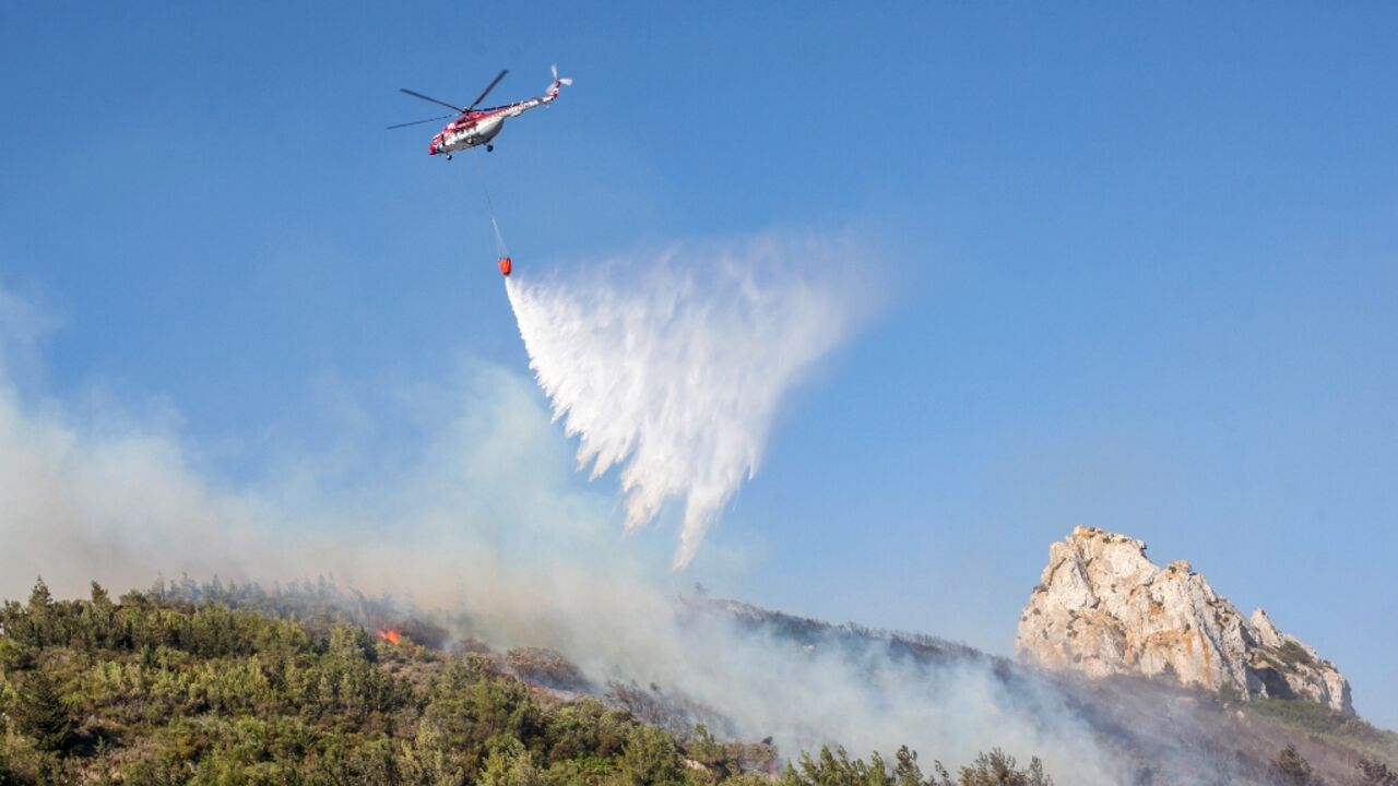A helicopter drops water on a forest fire in the Kyrenia mountains of the self-proclaimed Turkish Republic of Northern Cyprus on June 24, 2022