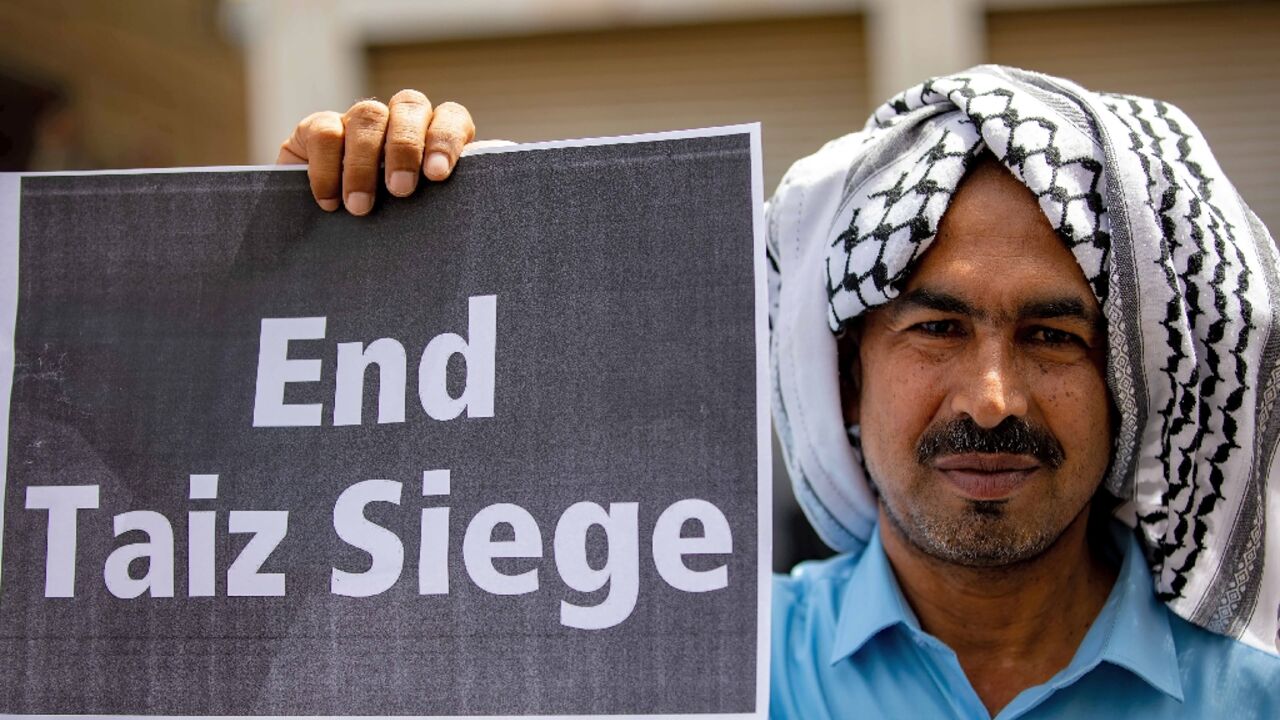 A demonstrator holds a sign in May 2022 demanding the end to the years-long blockade of the Yemeni city of Taez 