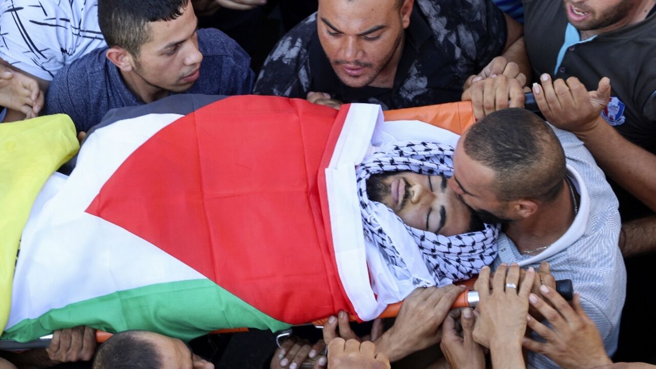 A mourner kisses the forehead of 17-year-old Kamel Alawnah during his funeral procession in the West Bank village of Jaba