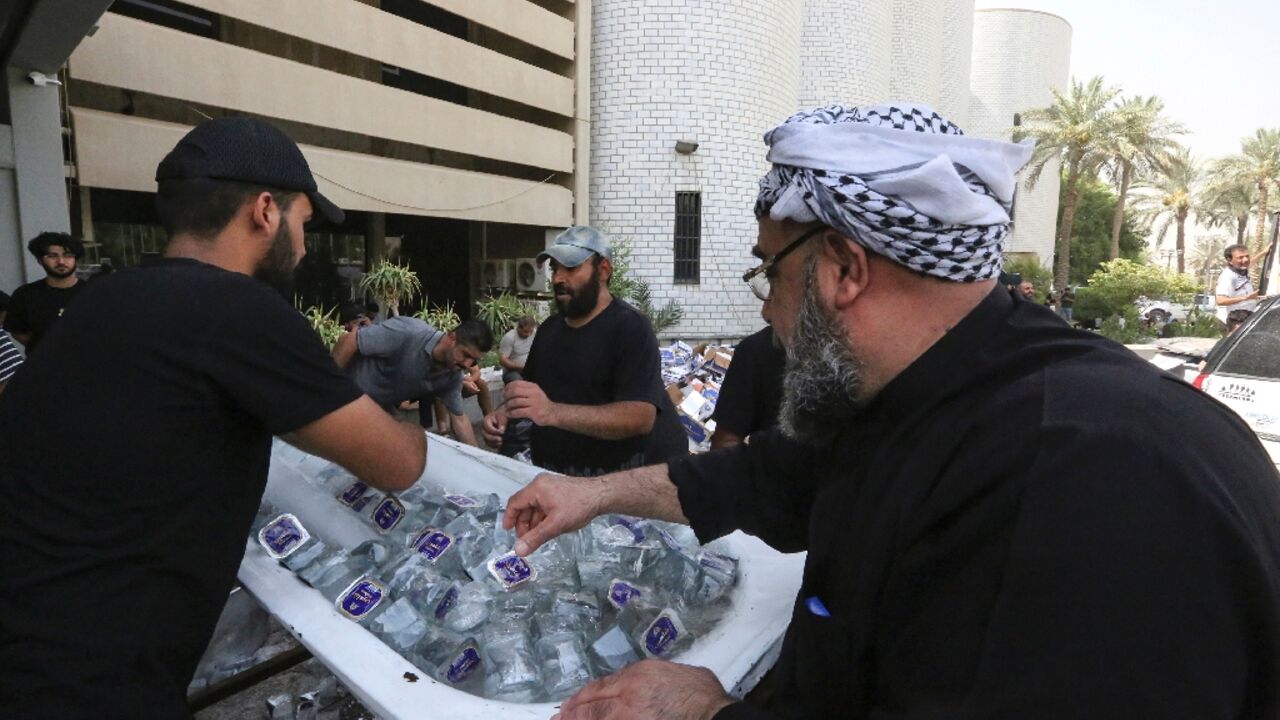 Supporters of Iraqi cleric Moqtada Sadr distribute water to fellow demonstrators, outside Iraq's parliament building on the second day of their occupation 