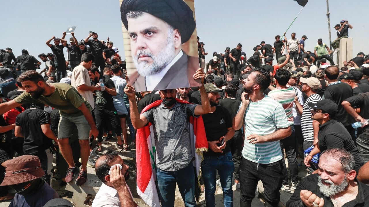 Supporters of the Iraqi cleric Moqtada Sadr raise a portrait of their leader, as they protest at a rival bloc's nomination for prime minister