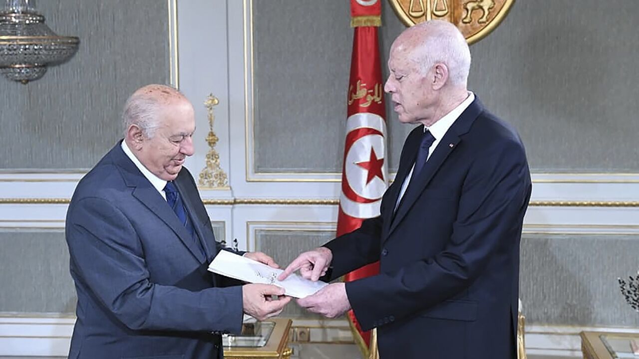 Sadeq Belaid hands a draft of the new constitution to President Kais Saied (R) at the Carthage Palace in Tunis on June 20 last month