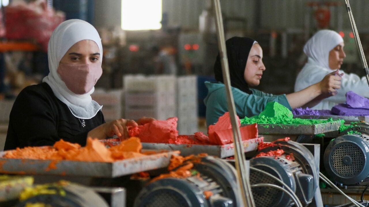 Jordanian workers put coloured chalk through a machine in the factory in Karak, south of the capital Amman 