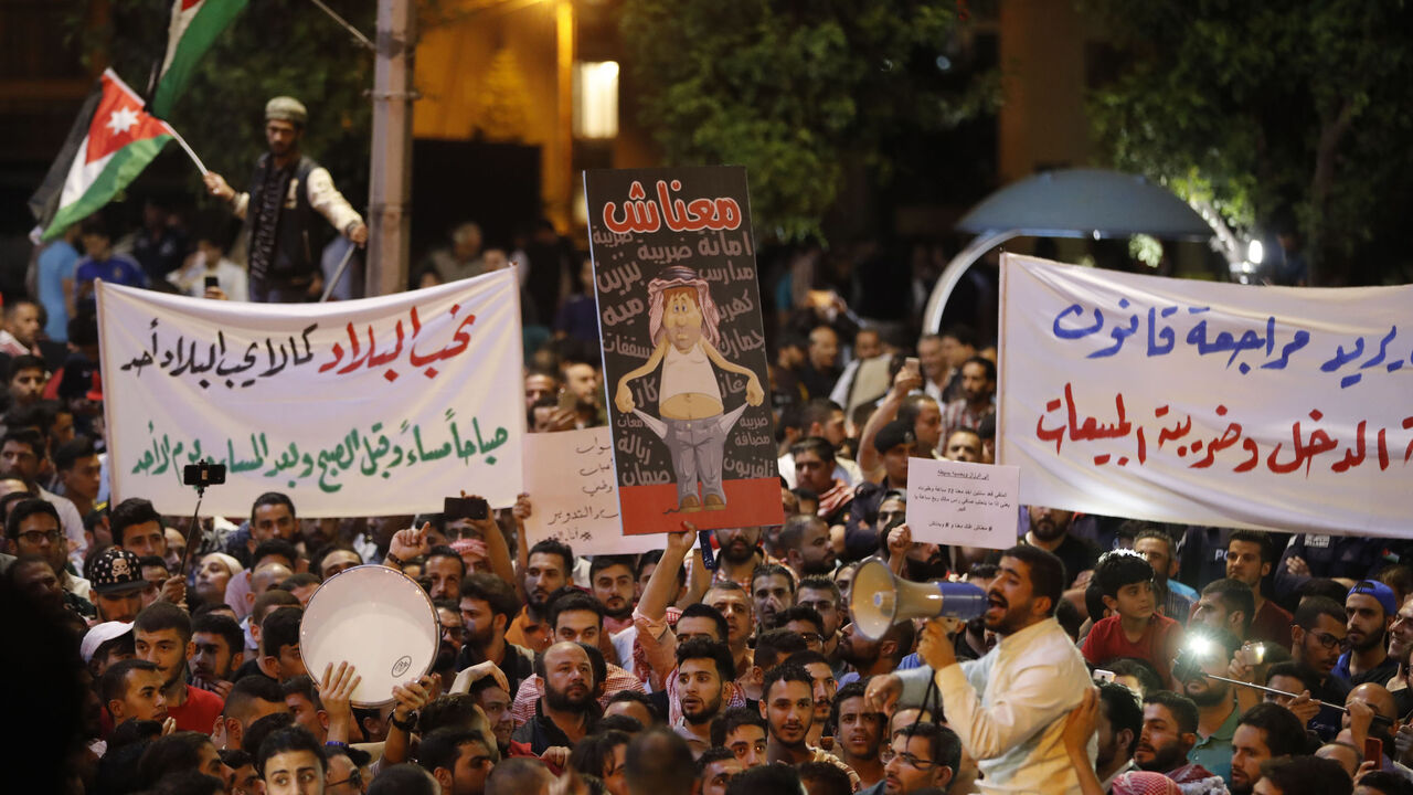 Demonstrators hold up posters in front of Jordanian policemen during a protest near the prime minister's office in Amman, Jordan, on June 6, 2018. 