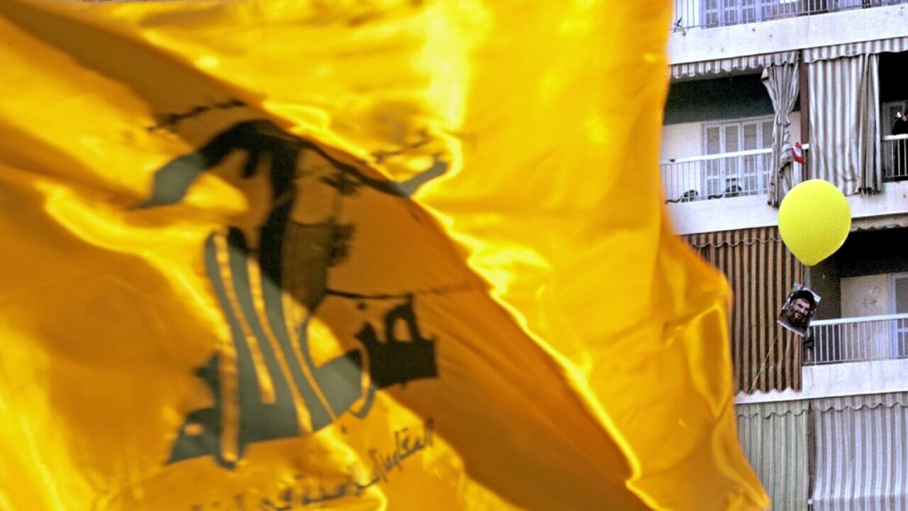 A Hezbollah flag flutters over a ceremony to mark the first anniversary of the war with Israel in Beirut's southern suburb of Dahiyeh, on August 14, 2007, while a portrait of Hezbollah chief Hassan Nasrallah tied to a balloon floats behind 