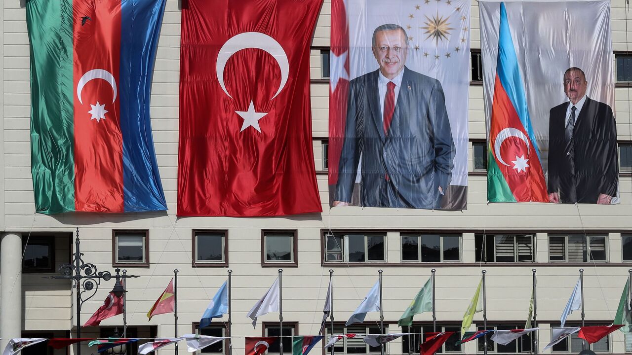 The national flags of Azerbaijan (L) and Turkey, and portraits of Turkish President Recep Tayyip Erdogan and Azerbaijani President Ilham Aliyev (R) hang side-by-side on the mayoral building in the Kecioren district of Ankara on Oct. 21, 2020. 