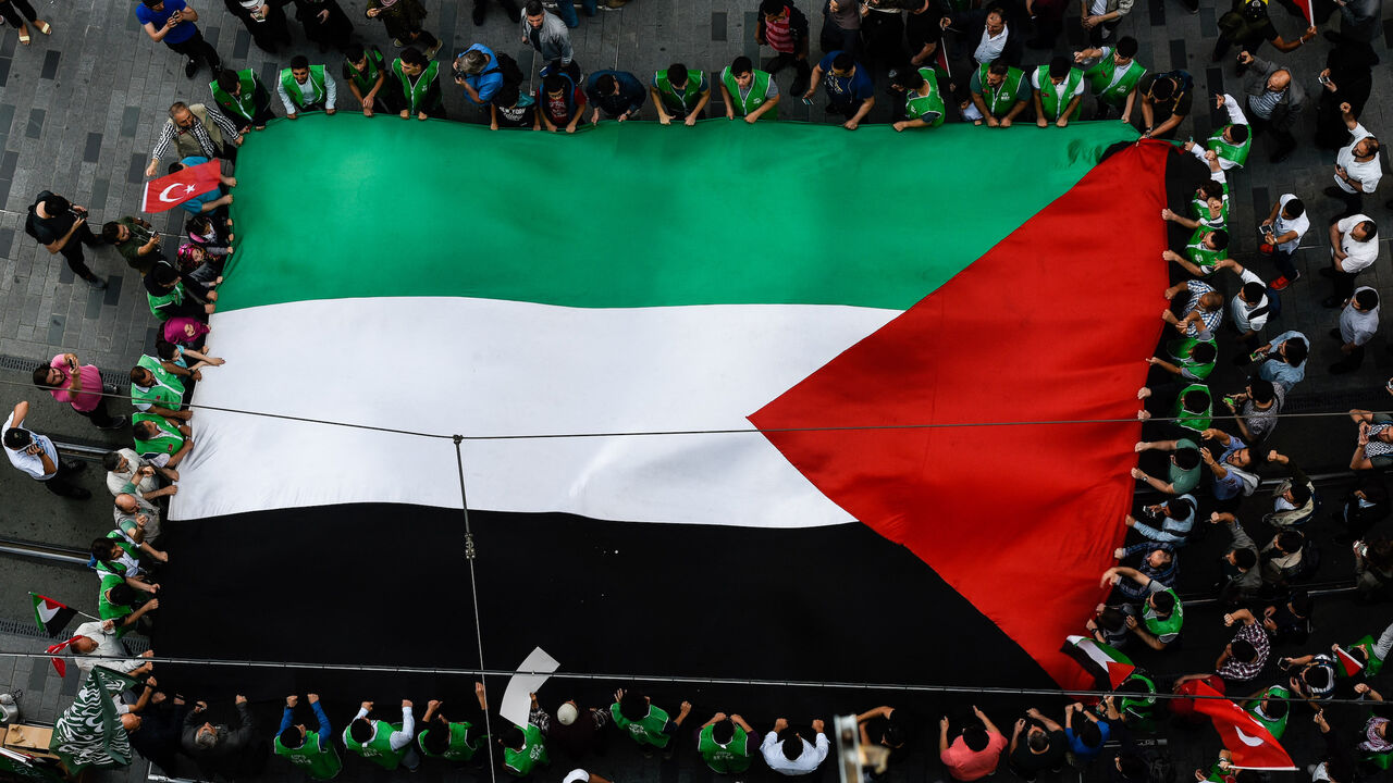 Demonstrators chant slogans as they march with a giant Palestinian flag.