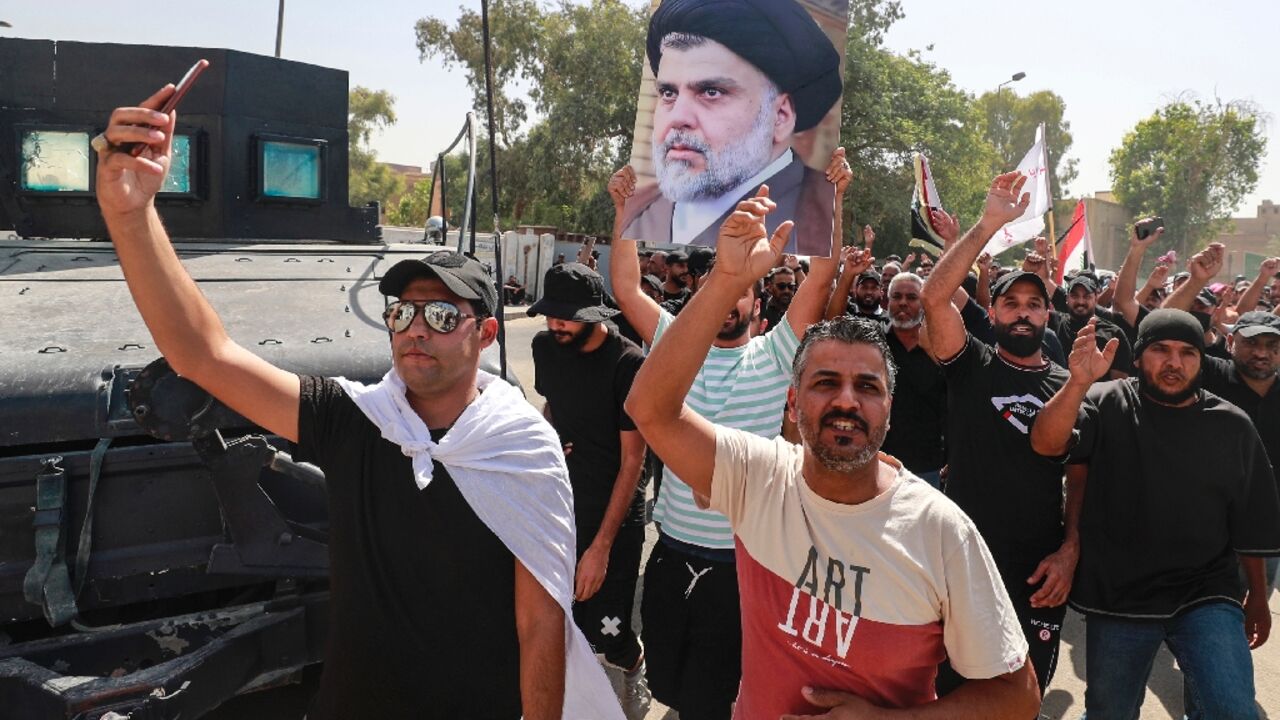 Supporters of the Iraqi cleric Moqtada Sadr raise a portrait of their leader