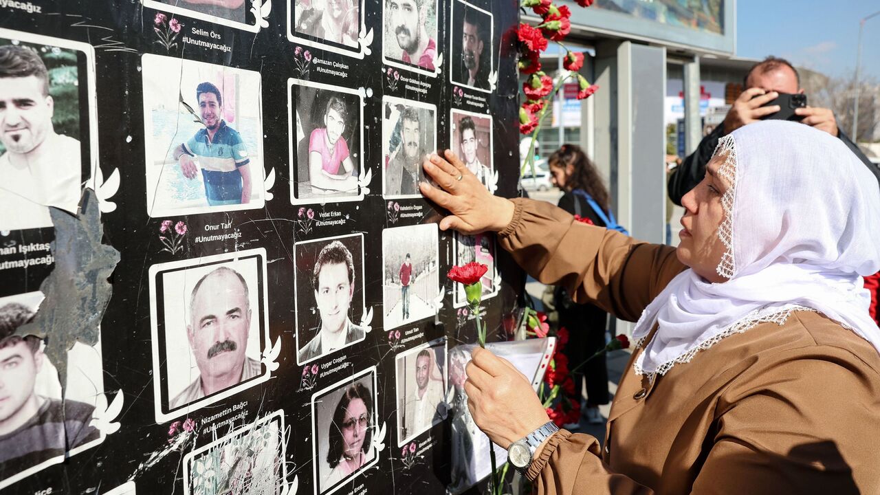 A woman holding a flower touches the picture of a suicide attack victim.