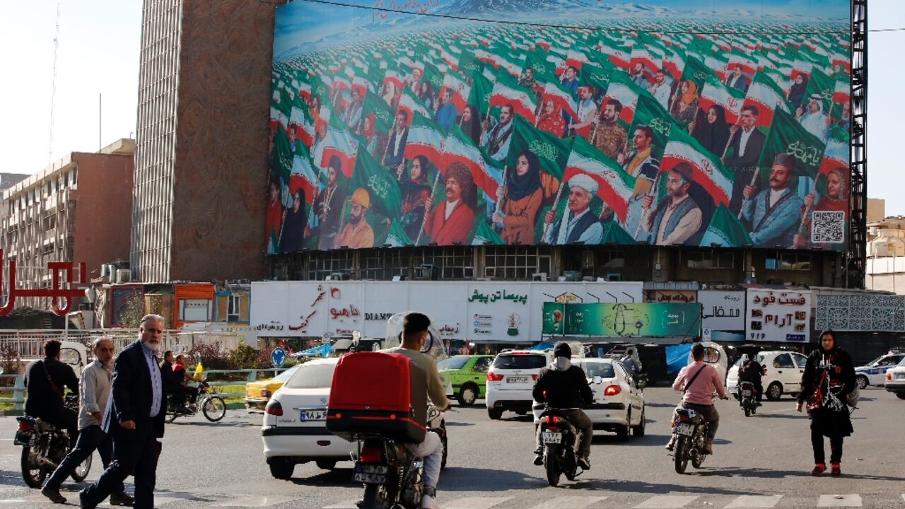 Pedestrians in Tehran's Valiasr Square near a huge billboard depicting Iranians marching with national flags