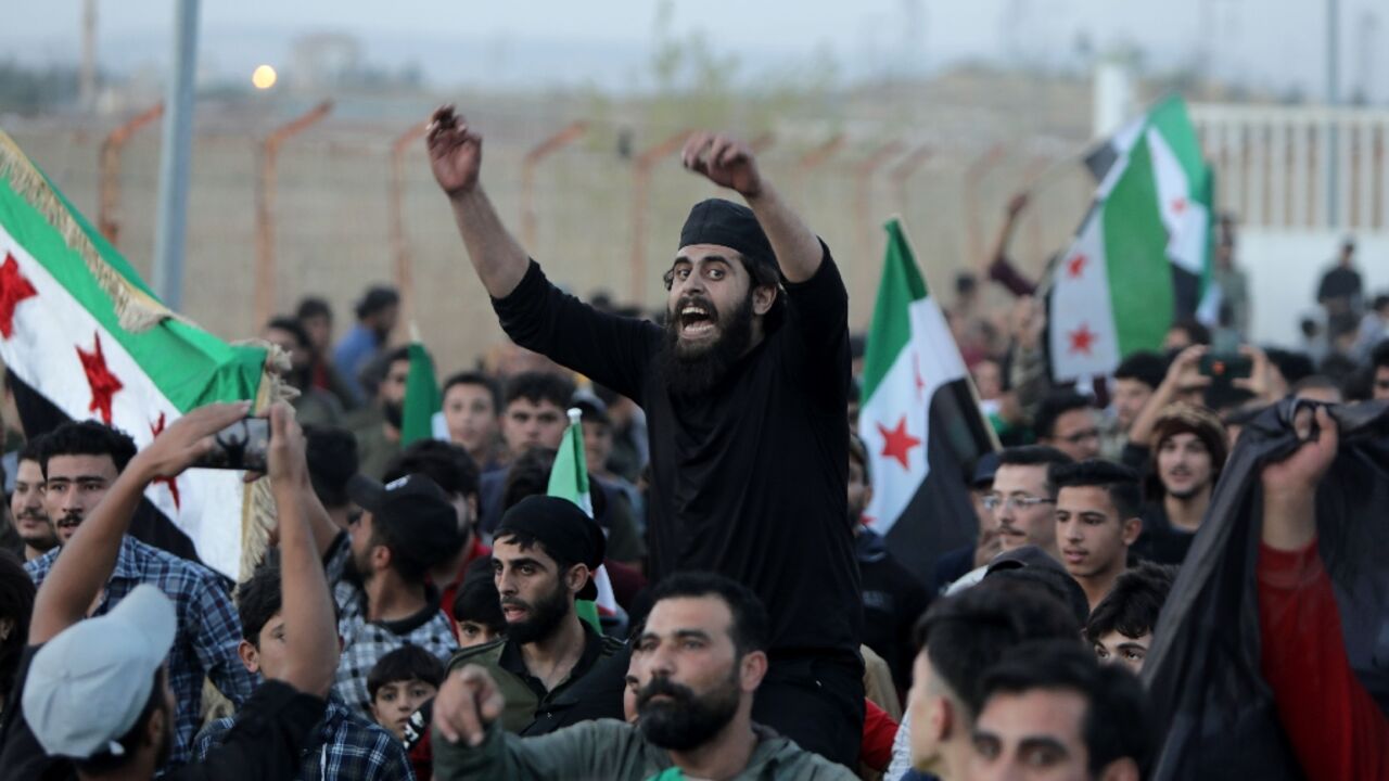 Demonstrators gather in the Syrian opposition-held border post with Turkey in Aleppo province on October 17, as civilians flee the advance of the the Hayat Tahrir al-Sham (HTS) jihadist group
