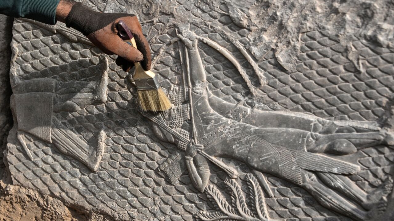 An Iraqi worker excavates a carving at the Mashki Gate, one of the monumental gates to the ancient Assyrian city of Nineveh