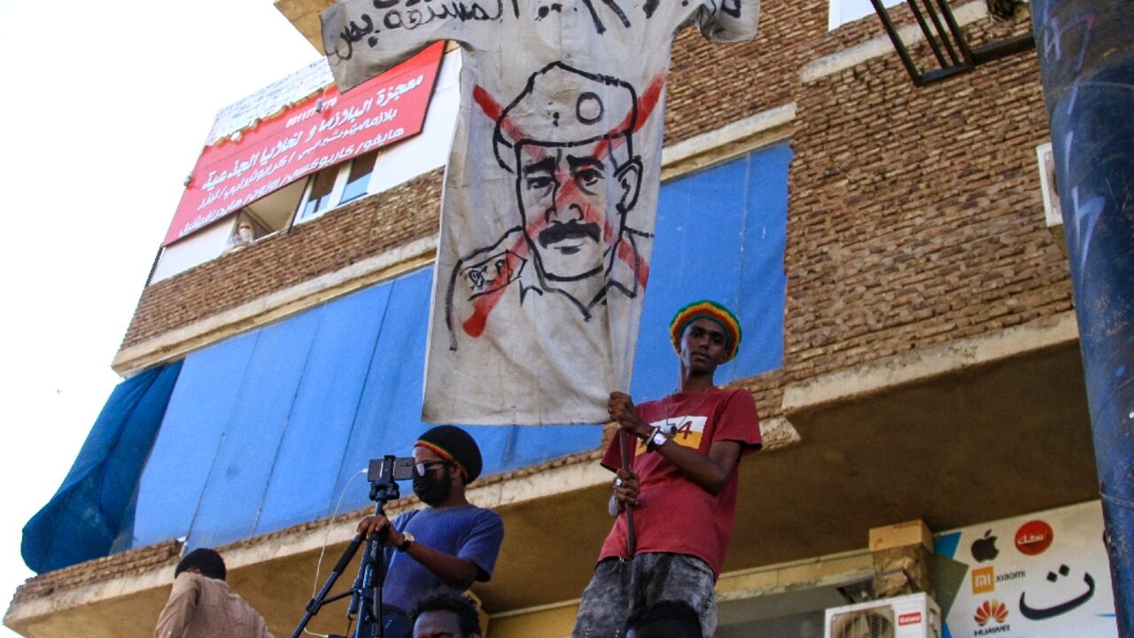 Sudanese protesters fly a banner bearing a crossed out image of coup leader Abdel Fattah al-Burhan, as they take to the streets to call for justice for those killed since last year's military power grab