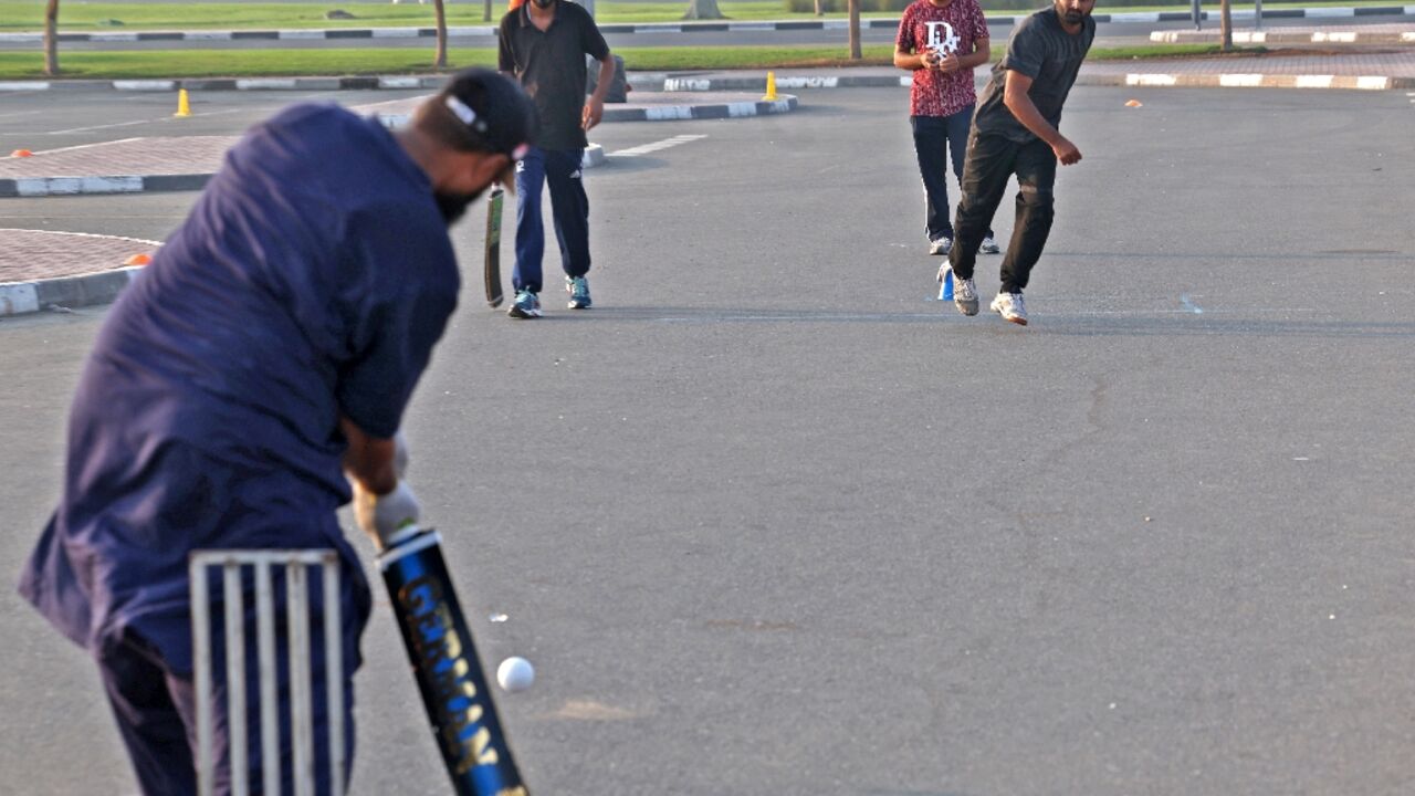 Expatriate workers play cricket in a parking lot in the Gulf emirate of Dubai