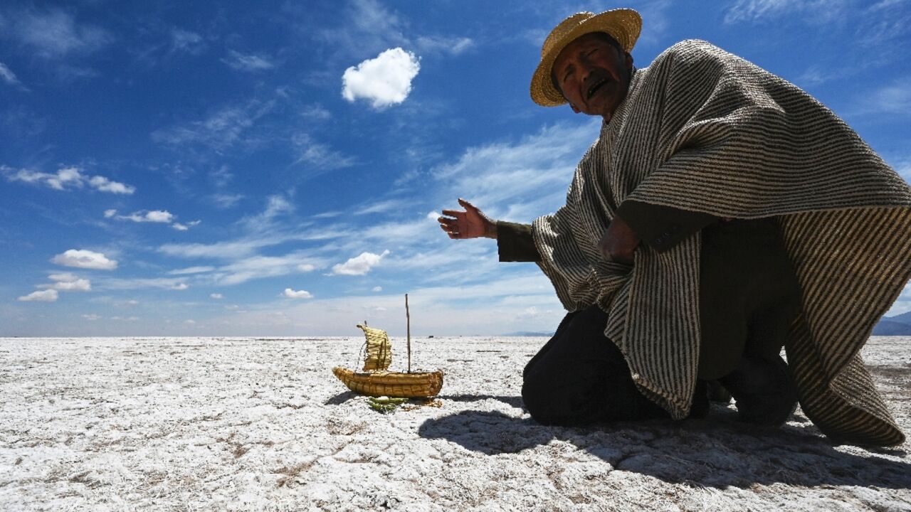 This year has seen unprecedented heatwaves: Lake Poopo, once Bolivia's second-largest, has largely disappeared. Felix Mauricio of the Uru Murato indigenous community shows a miniature replica of the type of boat once used there, on October 15, 2022