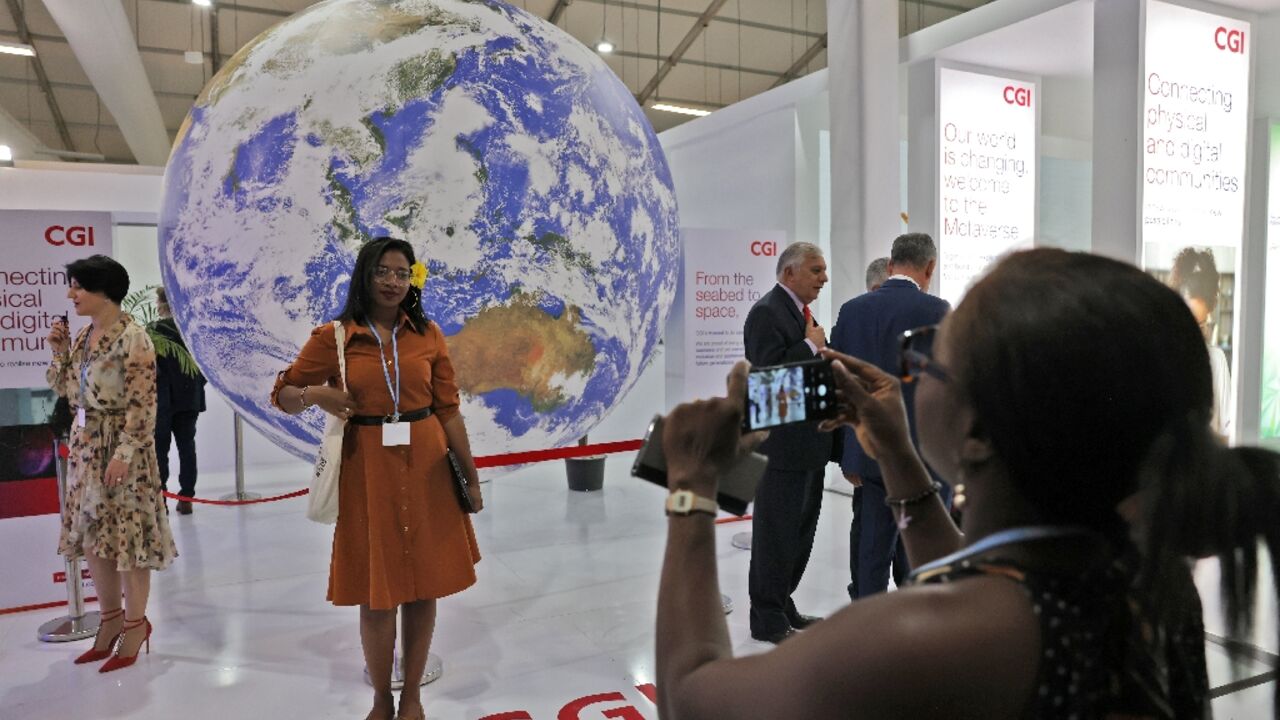 A woman poses for a picture in front of a globe inside the venue hosting the COP27 climate conference in Sharm el-Sheikh