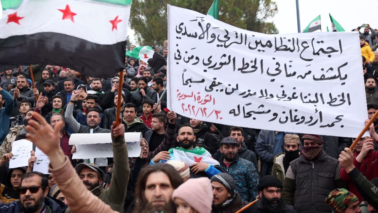Demonstrators raise Syrian opposition flags and placards as they rally against a potential rapprochement between Turkey and the Syrian regime