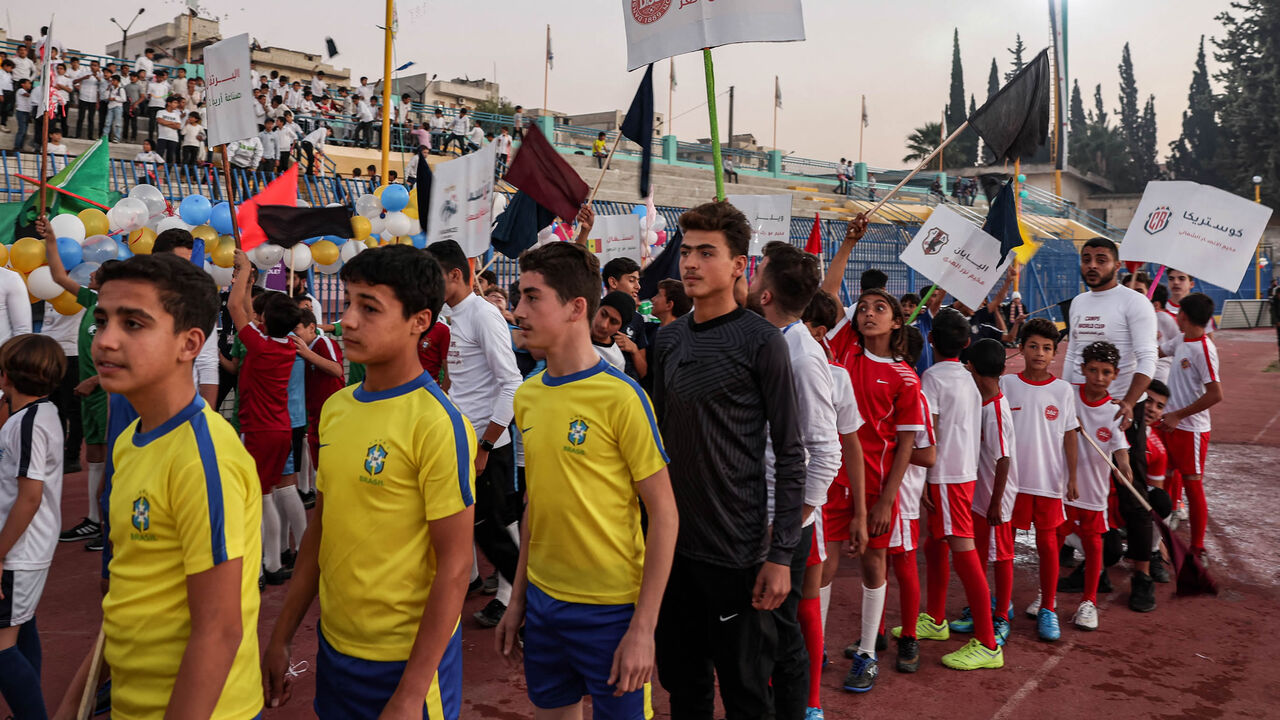 Children wearing the uniforms of national soccer teams playing at the Qatar 2022 FIFA World Cup line up during the opening ceremony of the "Camps World Cup" at the newly reopened Idlib Municipal Stadium, Idlib, Syria, Nov. 19, 2022.