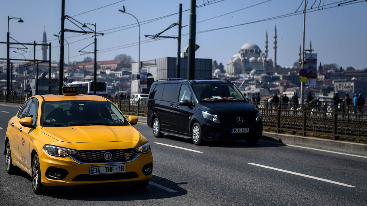 This picture shows an official yellow taxi and a van vehicle driven on the Galata Bridge in Istanbul, Turkey, March 30, 2018.