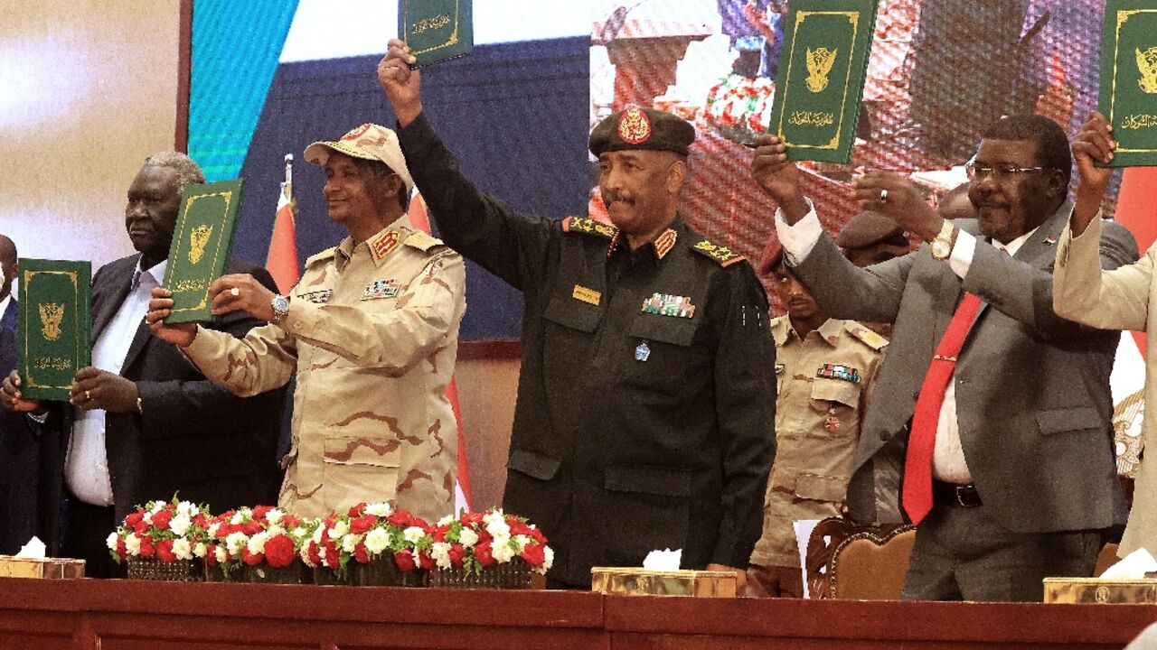 Sudan's army chief Abdel Fattah al-Burhan (C R) and paramilitary commander Mohamed Hamdan Dagalo (C L) alongside civilian leaders raise an initial deal aimed at ending a deep crisis caused by last year's military coup