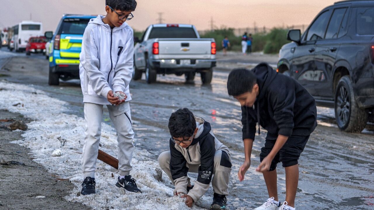Children toss handfuls of hail after a winter storm in the Umm al-Haiman district south of Kuwait City