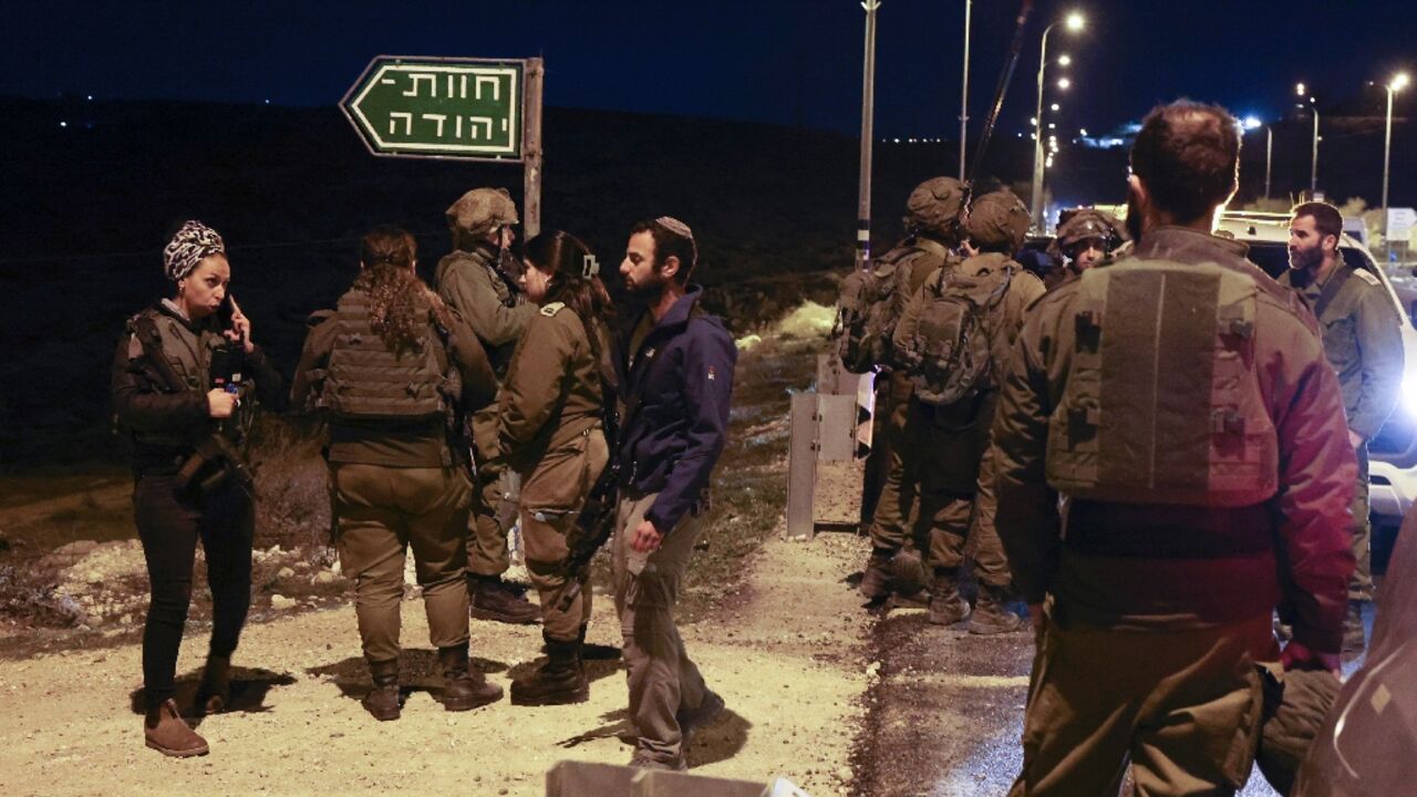 Israeli security forces and armed settlers gather near a settlement in the occupied West Bank after the stabbing attack 