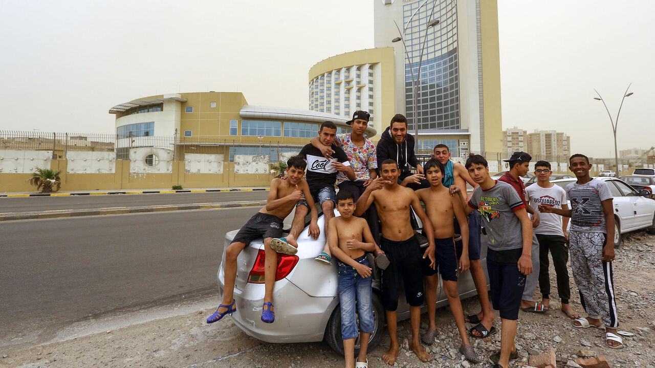 Libyan youths pose for a picture in front of the Corinthia Hotel after a swim near the city's main port, Tripoli, Libya, April 22, 2019.