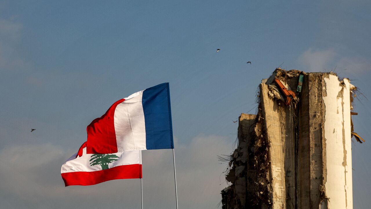 The flags of (front to back) France and Lebanon fly near the damaged grain silos at the port of Lebanon's capital Beirut on July 14, 2021, almost a year after the August 4 massive explosion that killed more than 200 people and injured scores of others. (Photo by PATRICK BAZ/AFP via Getty Images)