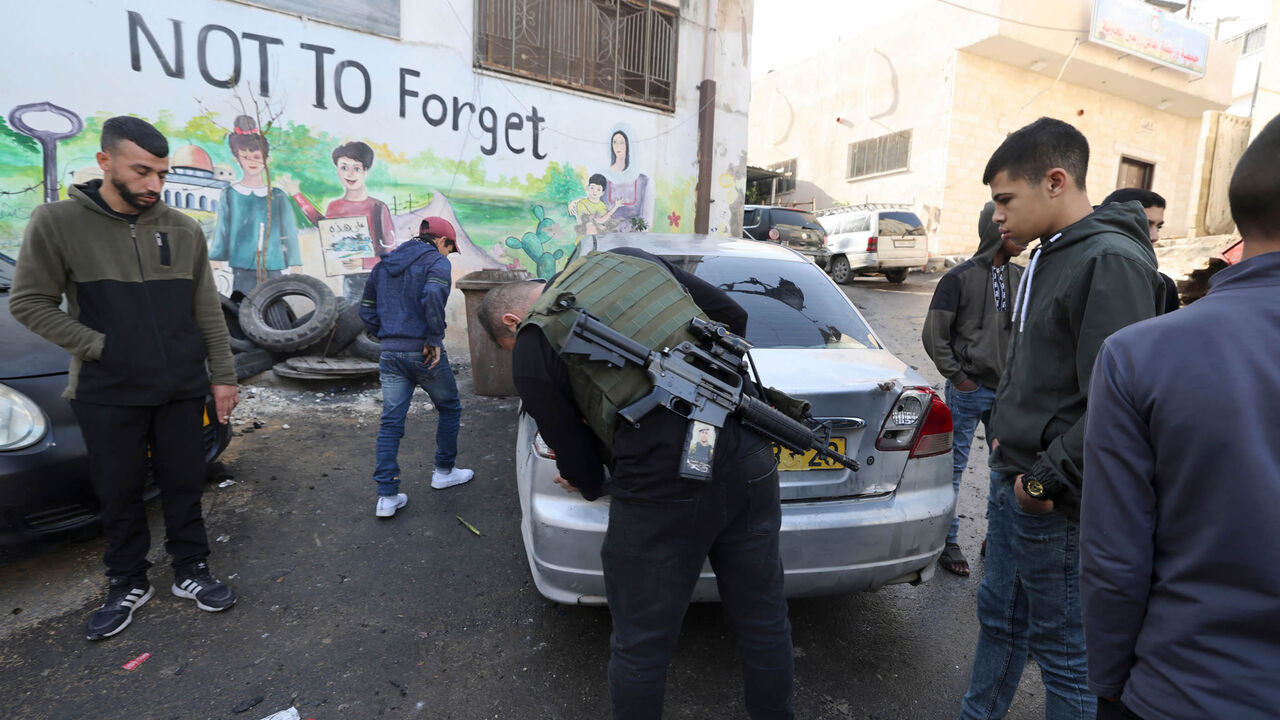 Palestinian residents and gunmen inspect the damage following the accidental explosion of an improvised explosive device in Jenin refugee camp, near the city of Jenin, West Bank, Dec. 12, 2022.