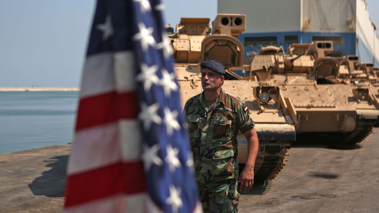 A Lebanese soldier walks past an American flag flying next to US made Bradley Fighting Vehicles at the port of Beirut on August 14, 2017. (Photo credit should read PATRICK BAZ/AFP via Getty Images)