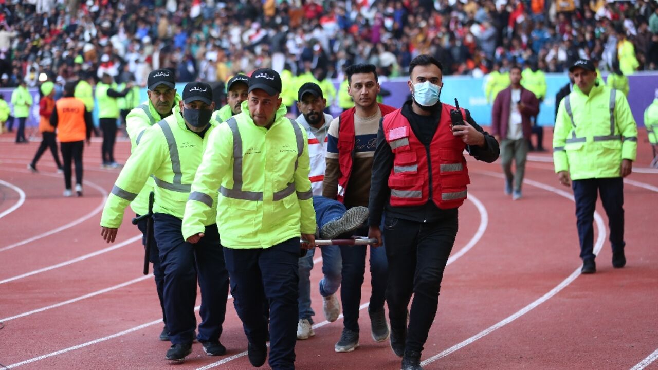 Iraqi security personnel carry an injured football fan into an emergency area at the Basra International Stadium following the stampede
