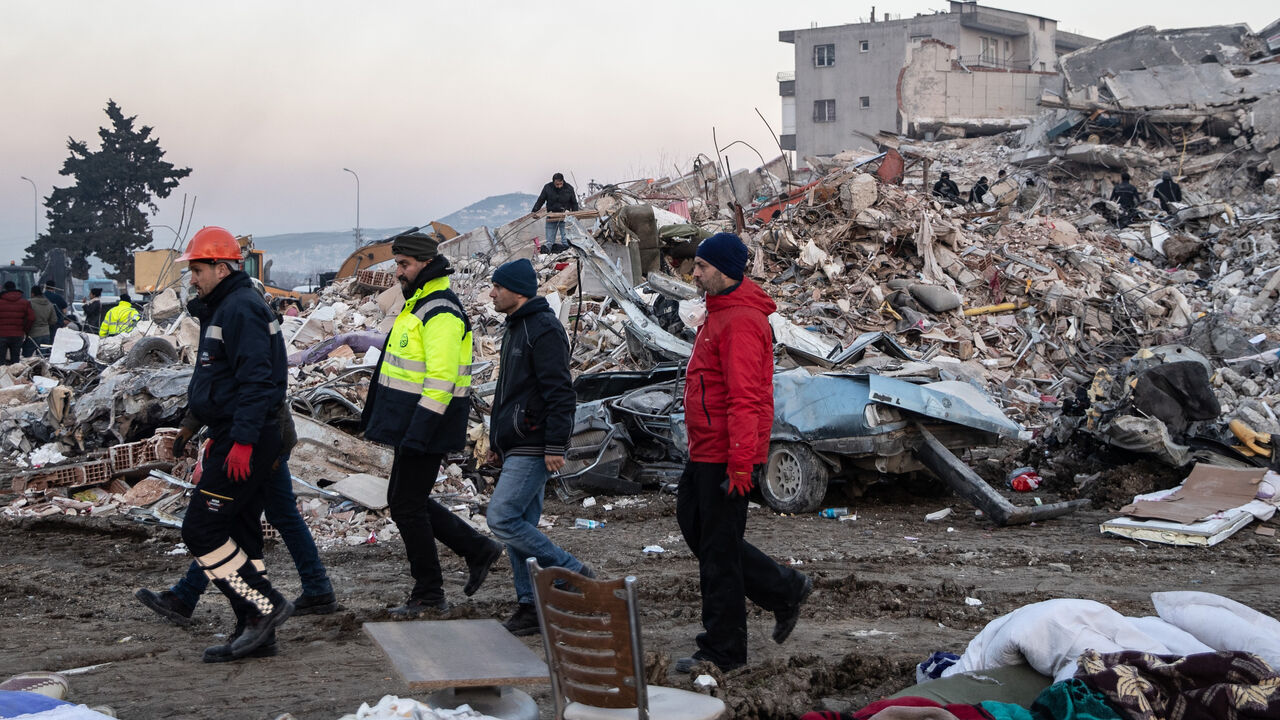 People walk past a collapsed building on Feb. 09, 2023 in Hatay, Turkey.