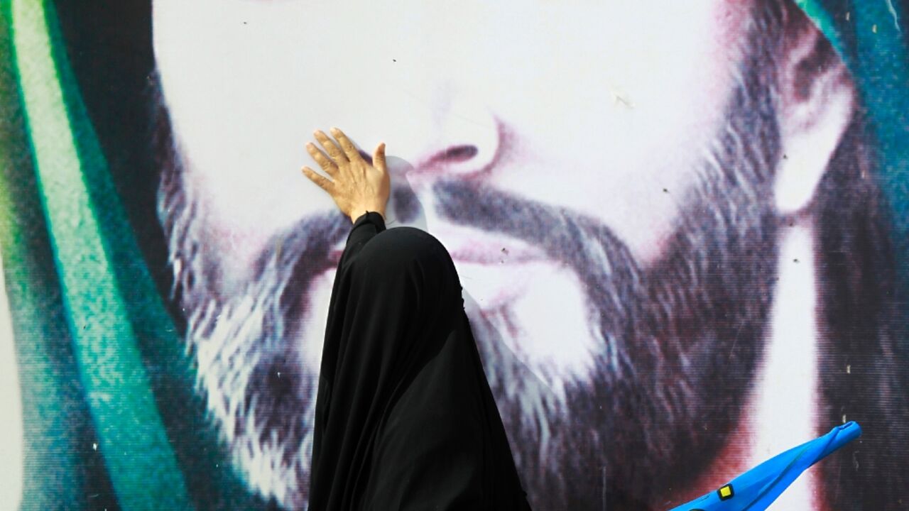 A Shiite Muslim pilgrim touches a portrait of Imam Hussein in the Iraqi holy city of Najaf during the Arbaeen religious festival, on November 26, 2015 