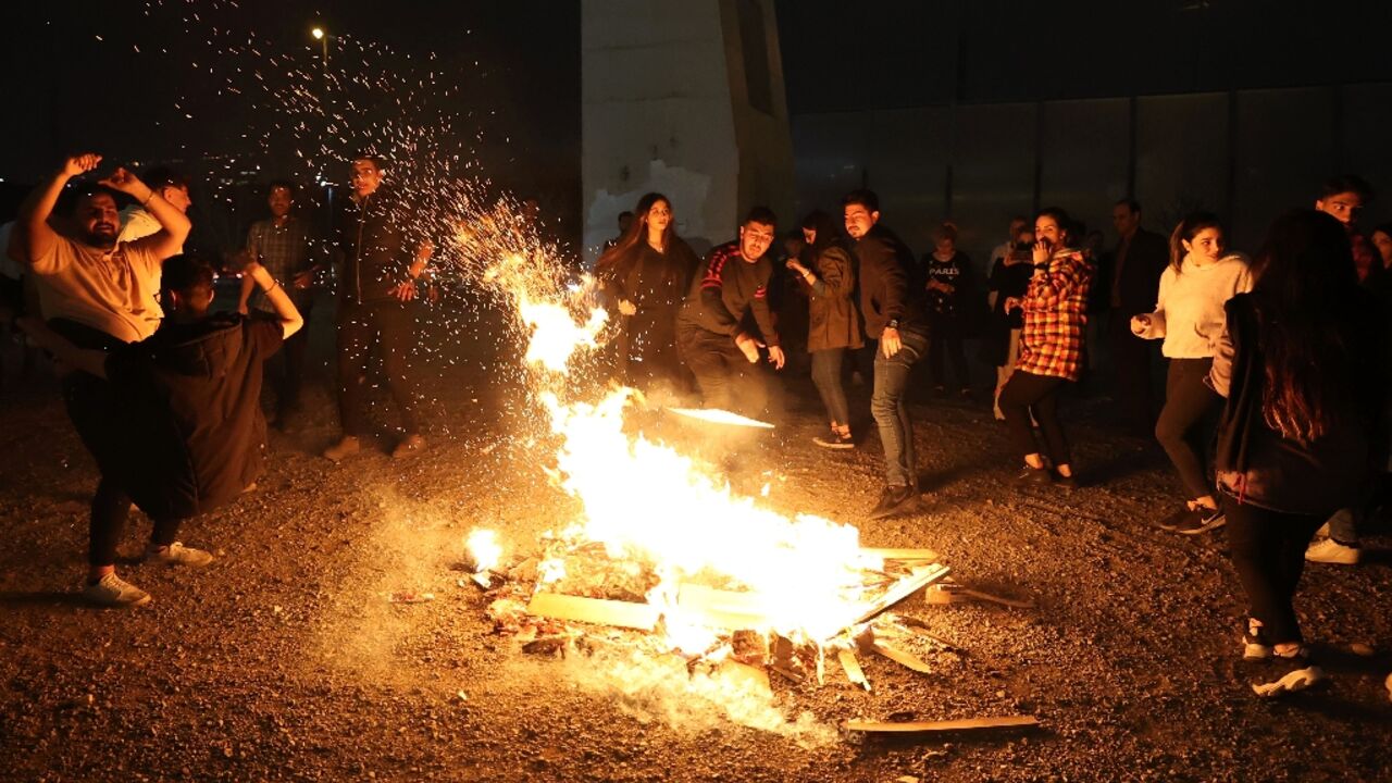 Iranians gather around a bonfire to mark the annual fire festival in the runup to Persian New Year, during which participants jump over the flames to ward off evil spirits