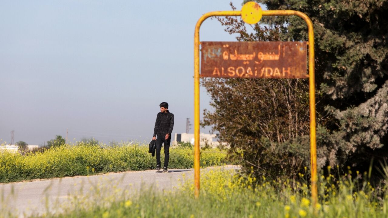 A man walks past the sign of Al-Suwaydah village near Jarablus in Syria's Aleppo province after the US helicopter raid
