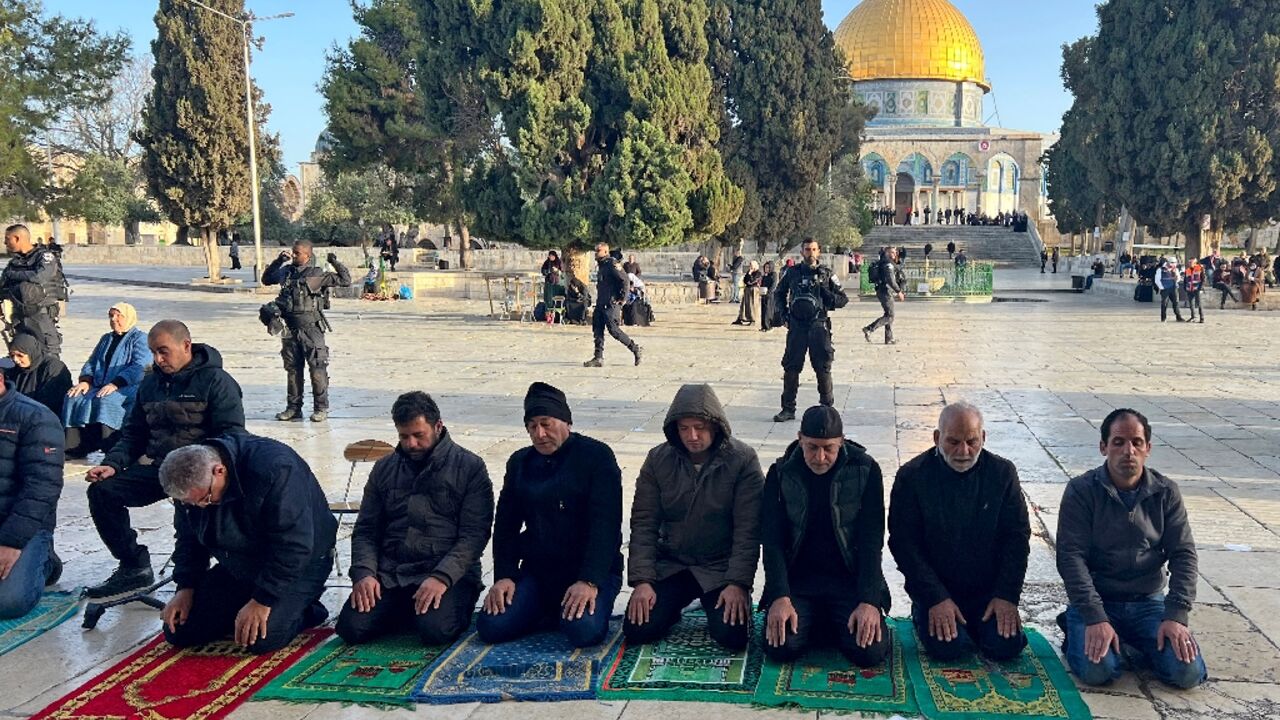 Israeli security forces stand guard as Palestinians pray in Jerusalem's al-Aqsa Mosque compound after officers earlier stormed the mosque's prayer hall 
