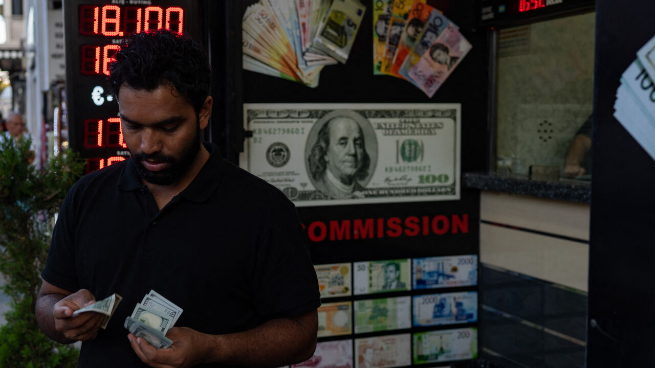 A customer holds US dollar banknotes outside a currency changer on a street in Istanbul on September 6, 2022, as Turkey's economy is suffering its biggest economic crisis in decades ahead of one of the toughest elections of President Recep Tayyip Erdogan's rule. - Turkey's official inflation rate barely changed on September 5, in a sign that a year-long crisis that has seen prices soar by 80 percent may finally be starting to ease. The TUIK state statistics agency said that consumer prices rose by 80.2 perc