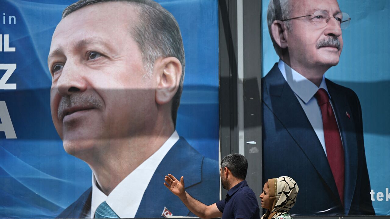 A couple walks past billboards with the portrait of Turkish President Recep Tayyip Erdogan (L) and with the portrait of Republican People's Party (CHP) leader and presidential candidate, Kemal Kilicdaroglu (R) in Sanliurfa, south-eastern Turkey on April 28, 2023. (Photo by OZAN KOSE / AFP) (Photo by OZAN KOSE/AFP via Getty Images)