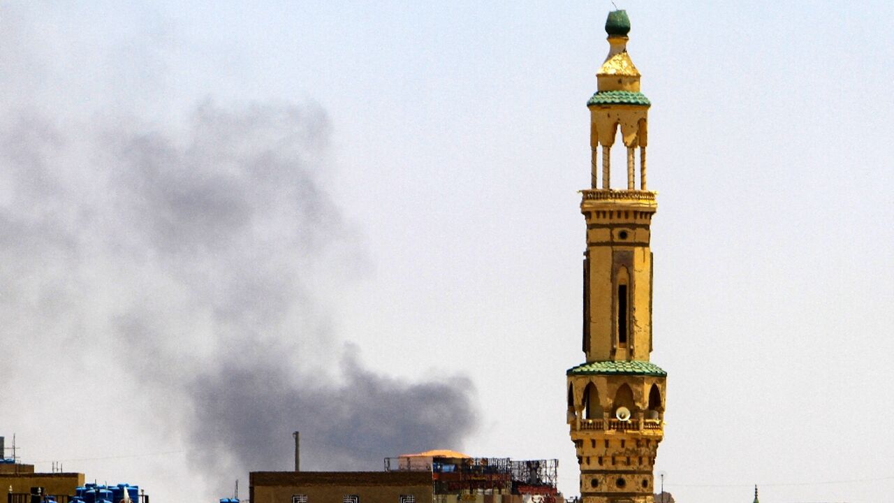 Smoke billows above buildings behind a mosque during fighting in Khartoum